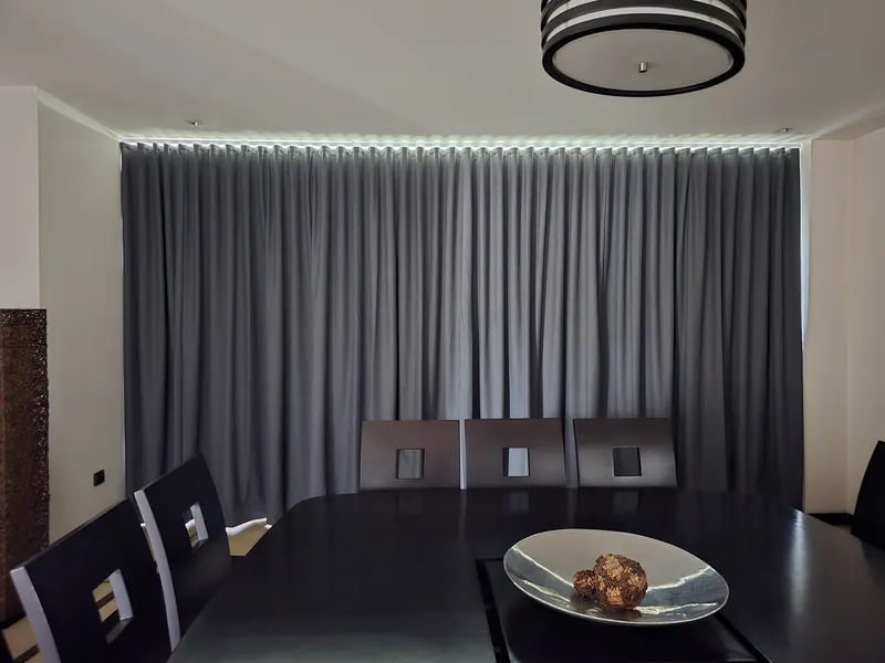 Cortina blackout gris con luz perimetral en un comedor de Puebla