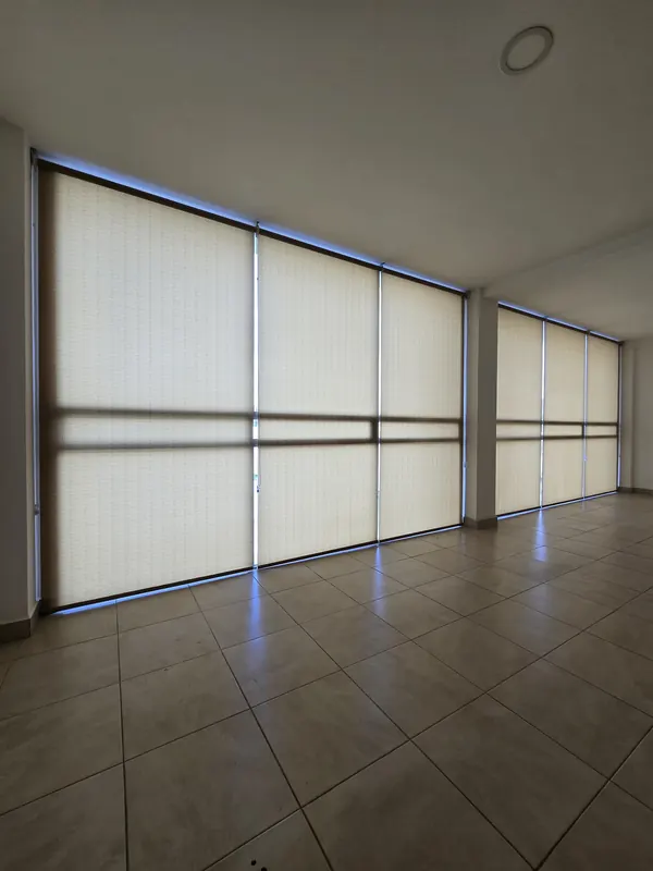 Persianas de filtro ligero cubriendo un muro de ventanas en una estancia de Puebla