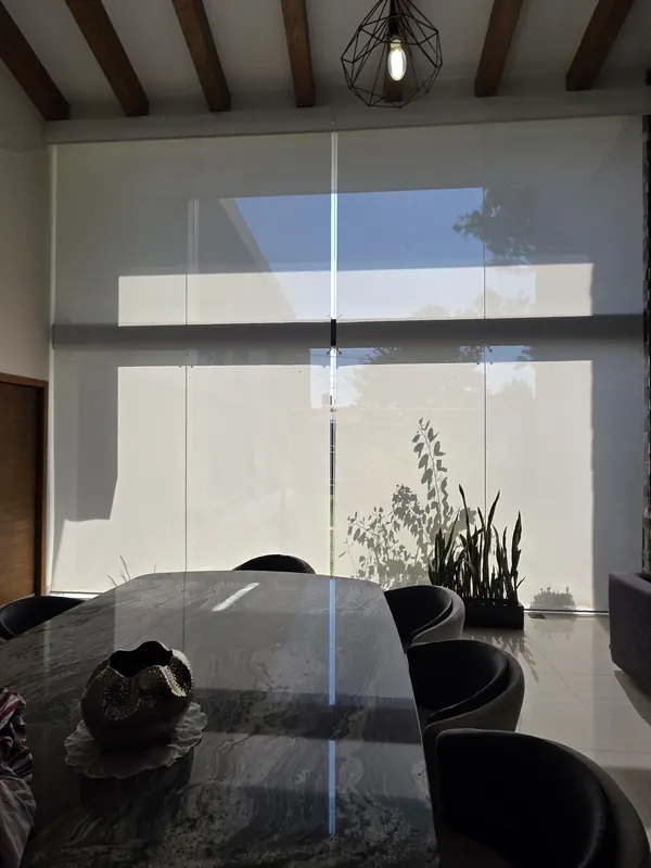 Persiana de malla solar filtrando el sol de la tarde en un comedor de Puebla