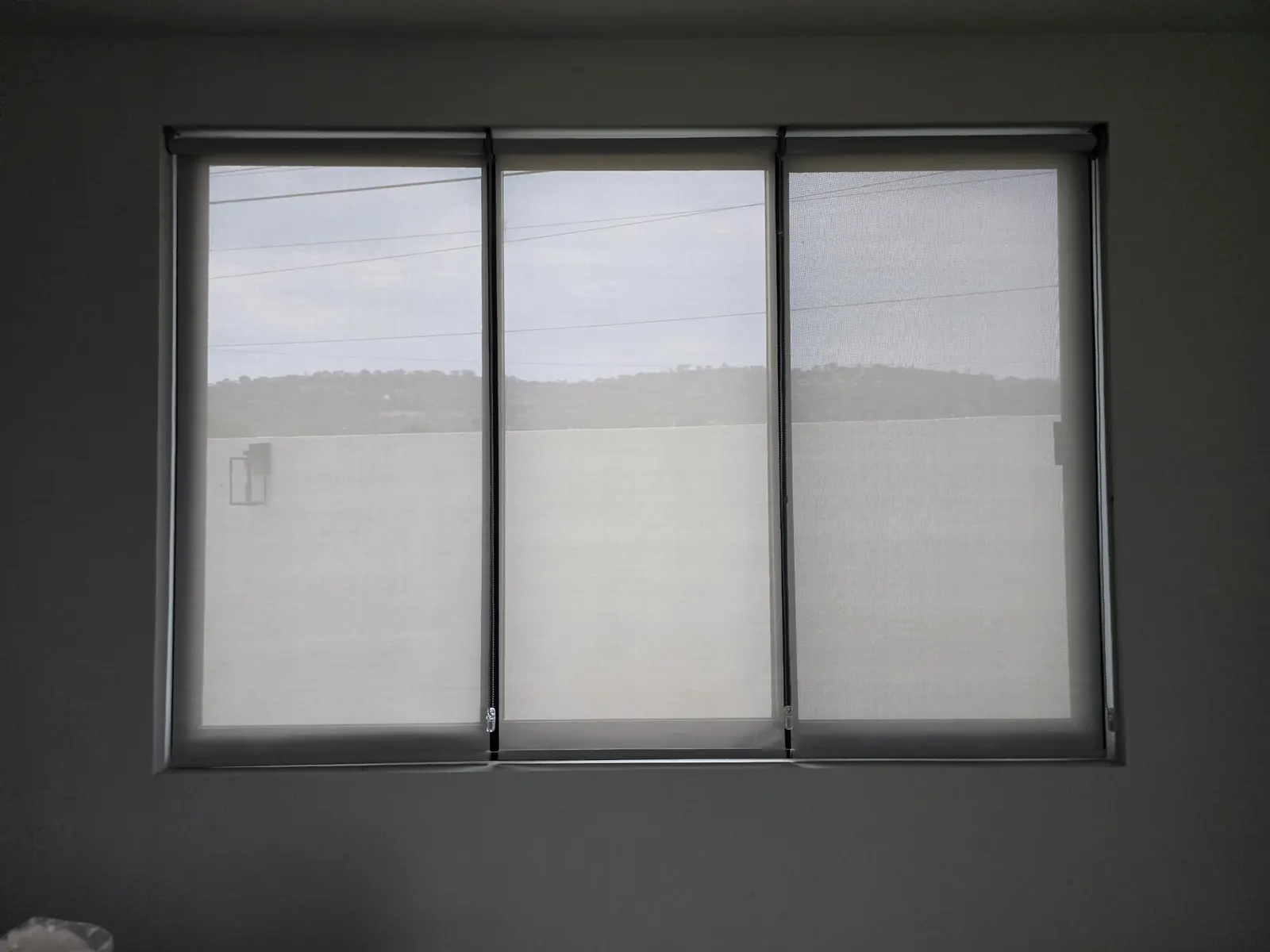 Ventana de tres hojas con persianas enrollables de malla solar instaladas por Style Coverings en Puebla