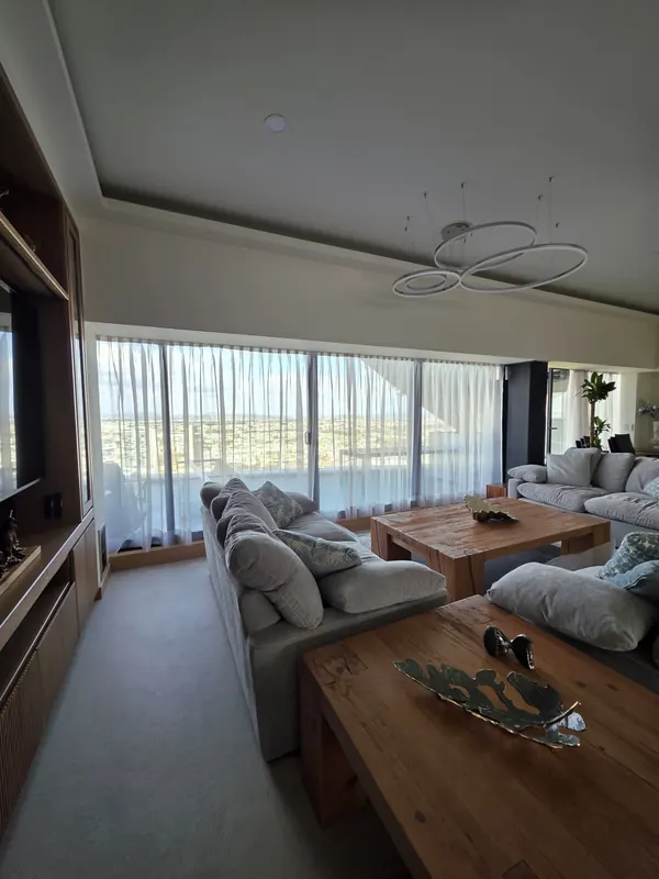 Sala de un departamento con cortinas de tergal de piso a techo y vista panorámica