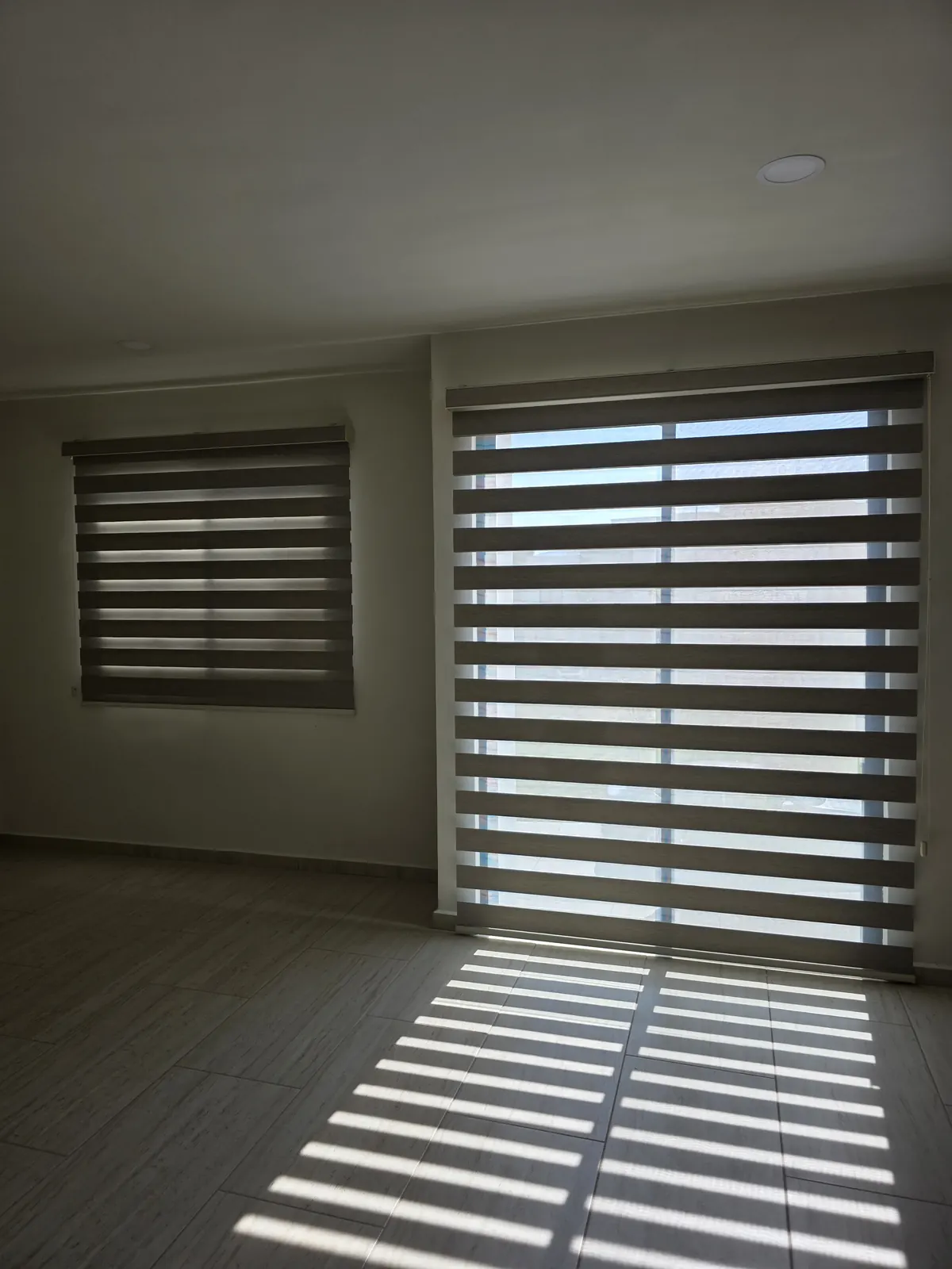Franjas de luz en el piso que deja una persiana Sheer Elegance abierta en una estancia de Puebla