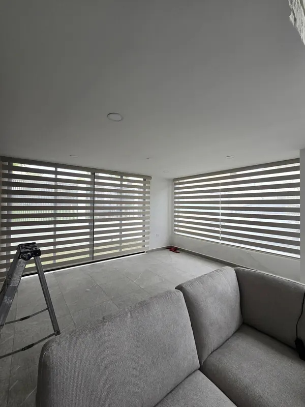 Persianas Sheer Elegance en las ventanas en esquina de una sala en Puebla