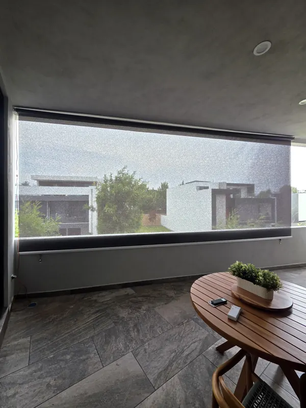 Toldo vertical de malla screen cerrando una terraza con mesa en Puebla